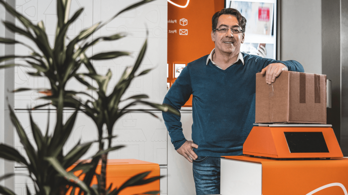 Man leunt op pakketje bij een postnl punt