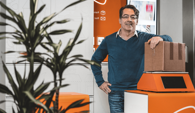 Man leunt op pakketje bij een postnl punt